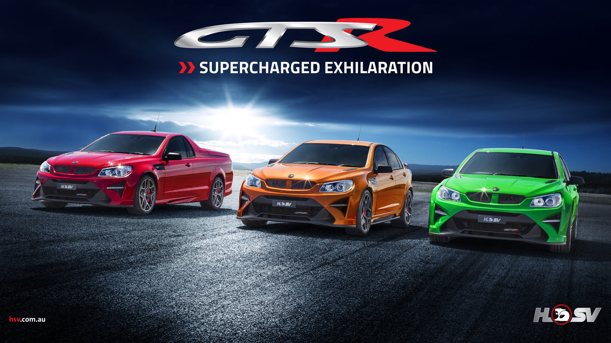 Three modified Holden GTSR's in red, orange, and green are lined up on a dark asphalt road under a dramatic blue sky with a bright sunburst. The text 'GTSR SUPERCHARGED EXHILARATION' is displayed at the top, with the HSV logo at the bottom right.